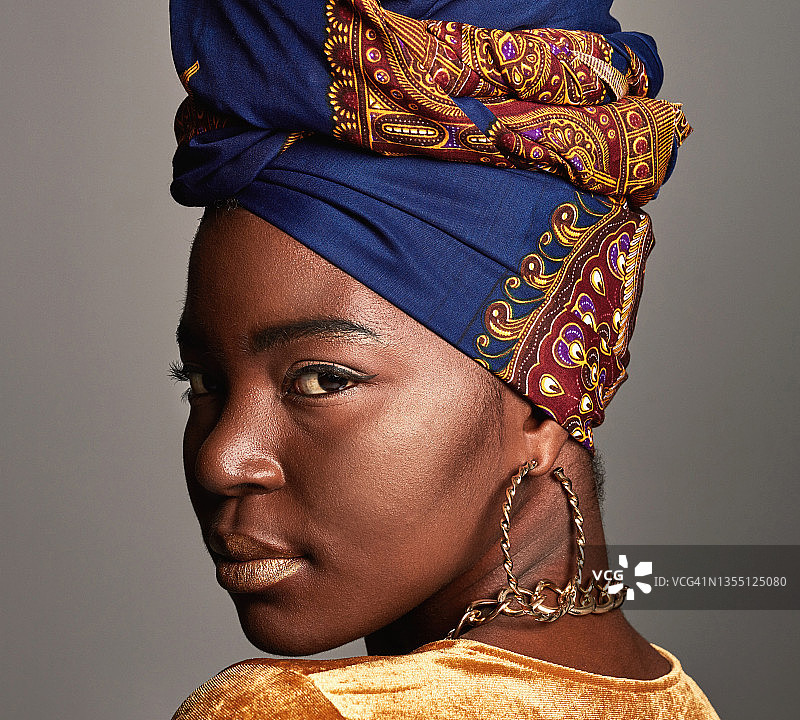 年轻女人戴着非洲传统头巾，以灰色为背景的照片图片素材