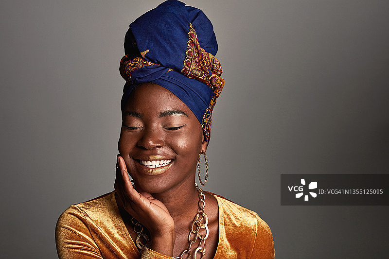 年轻女人戴着非洲传统头巾，以灰色为背景的照片图片素材