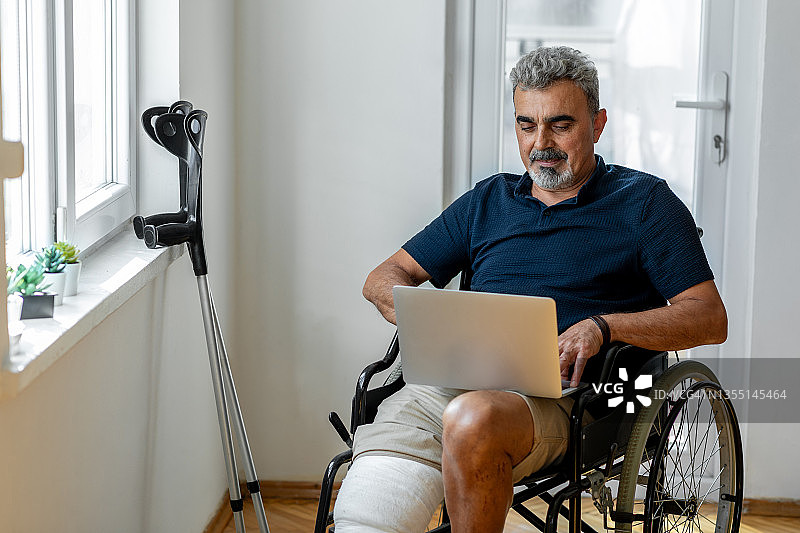 坐在轮椅上腿部骨折的年长男人图片素材