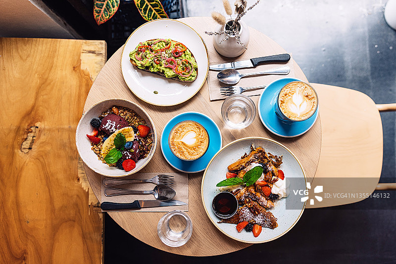 咖啡馆里的牛油果吐司、阿萨伊浆果碗和法式吐司健康早餐图片素材