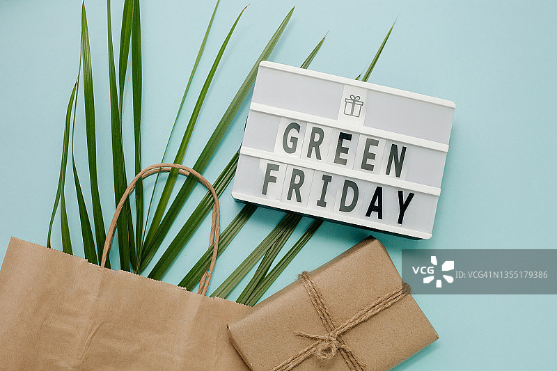 绿色星期五灯箱和带树叶的购物袋：过度生产和可持续生活理念图片素材