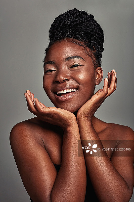 一个迷人的年轻女子在灰色背景下摆姿势的工作室拍摄图片素材