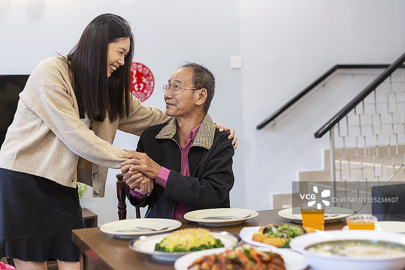 快乐的成年女子在家探望年迈的父亲图片素材