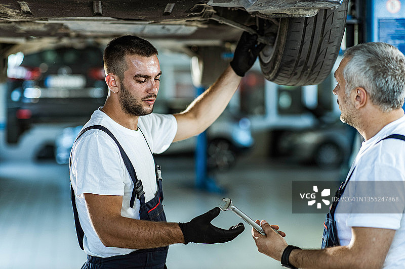 汽车修理工在修理厂合作修理轮胎图片素材