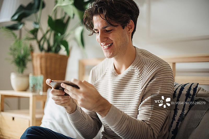 年轻男人用智能手机玩电子游戏并为成功而欢欣鼓舞图片素材