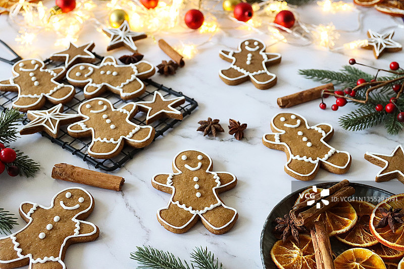 姜饼小人和星星饼干，白色糖霜，八角茴香，肉桂棒，橙片，云杉针，金色和红色小球，大理石背景图片素材