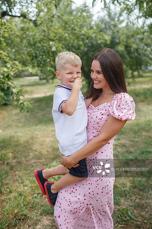 快乐的母亲和她可爱的儿子在花园里图片素材
