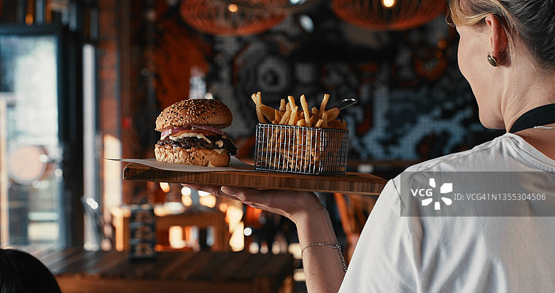 女服务员在餐厅里端着汉堡和薯条的照片图片素材