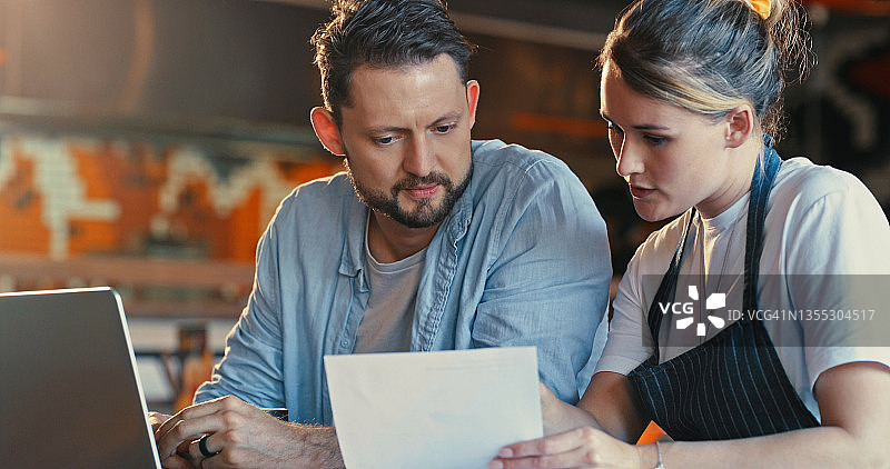 年轻男女在餐厅使用笔记本电脑查看文件图片素材