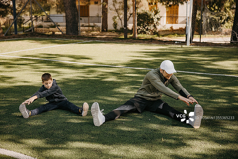 父子在足球场上锻炼和伸展身体图片素材