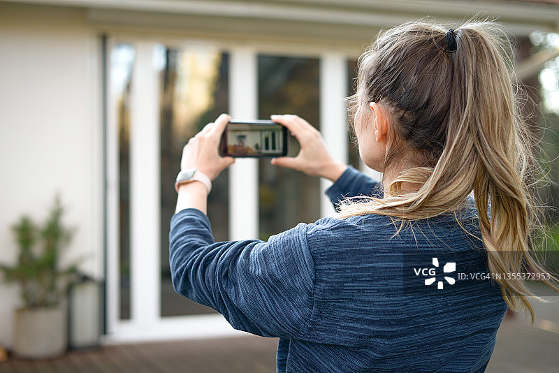 女人用智能手机拍摄房屋图片素材