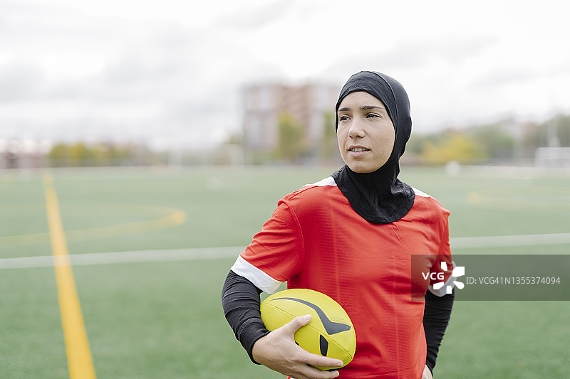 在球场上手持橄榄球的健壮穆斯林女人图片素材