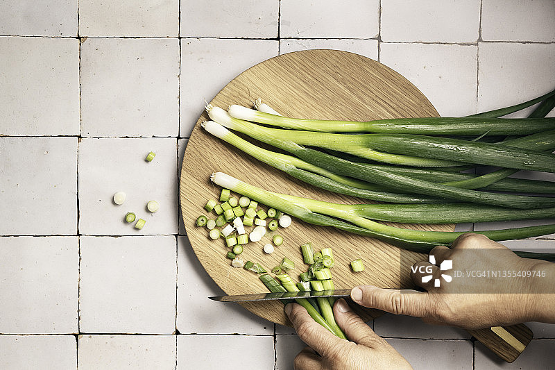 木板上的新鲜葱，一些是完整的，一些是切好的，有刀，人手图片素材