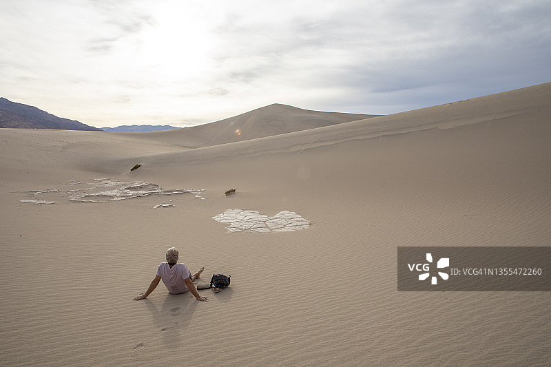 清晨远足后，男人在沙漠沙丘上放松图片素材