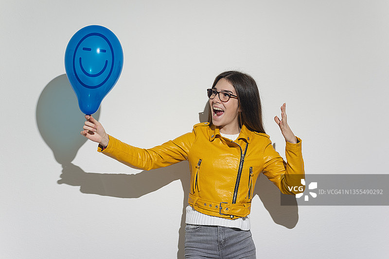 女人手拿拟人面孔气球图片素材