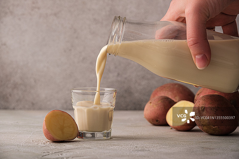 女子将马铃薯植物奶倒入玻璃杯中图片素材