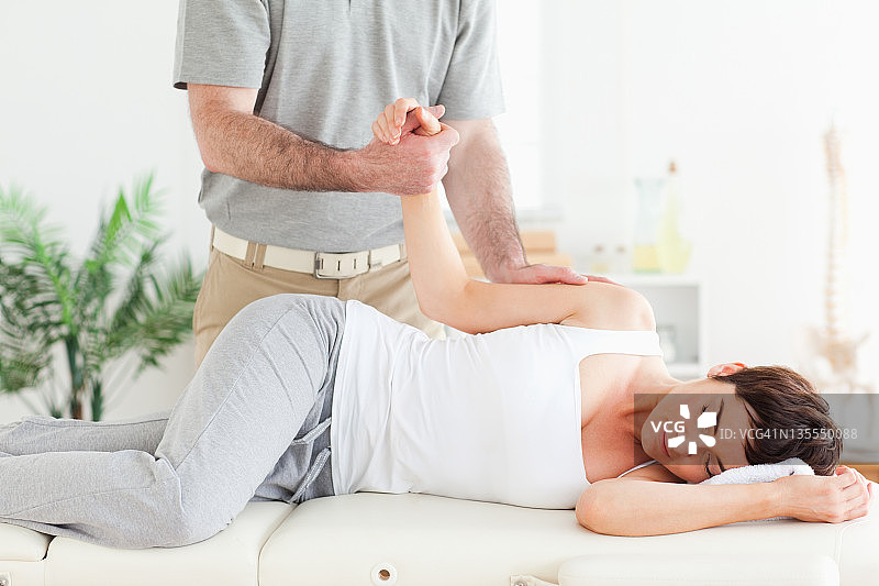 脊椎按摩师伸展女性顾客的手臂图片素材