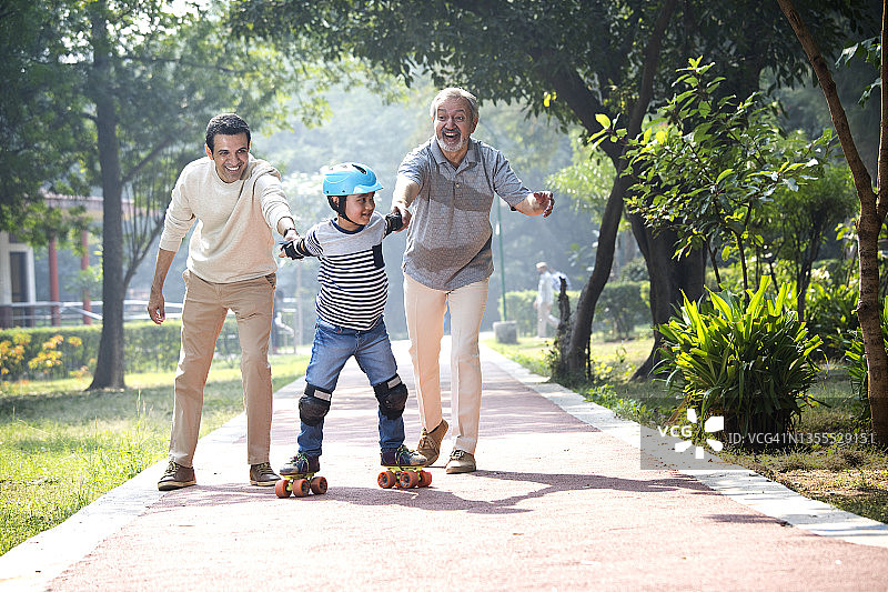 在公园里，男孩和父亲、祖父一起学习轮滑图片素材