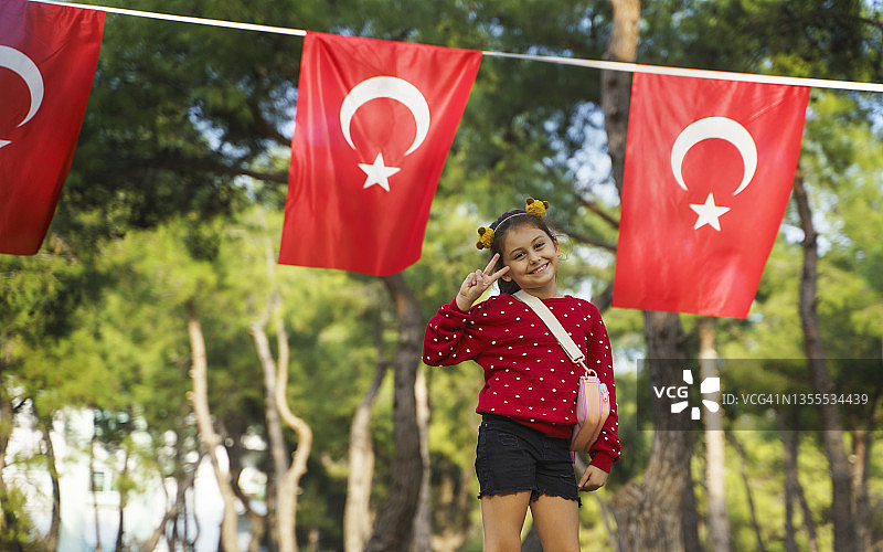 在土耳其国旗前摆姿势的可爱小女孩户外肖像图片素材