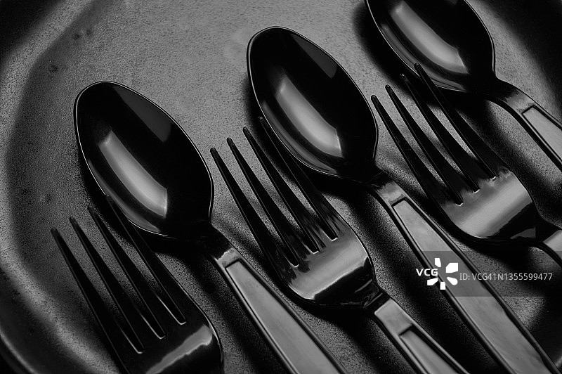 黑色地板上的黑色塑料勺子和叉子图片素材