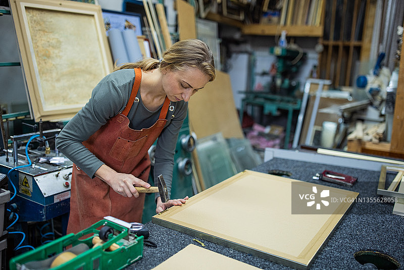 在玻璃工坊里制作相框的女工匠图片素材