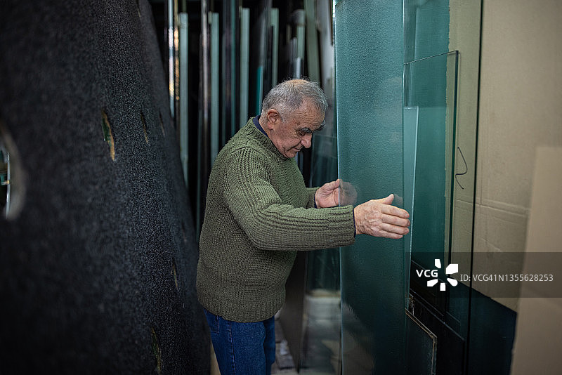 搬运大块玻璃的年长男玻璃工匠图片素材