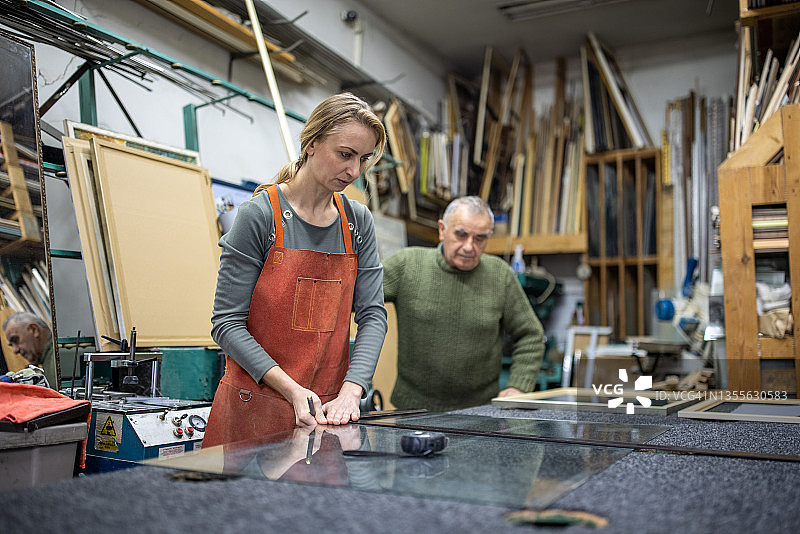 年长的男性工匠指导女员工切割玻璃图片素材