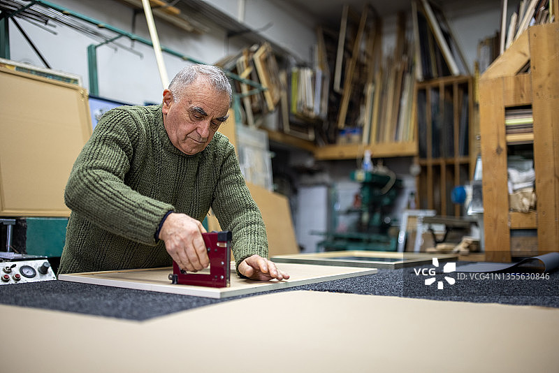 男工匠使用订书机枪制作相框图片素材