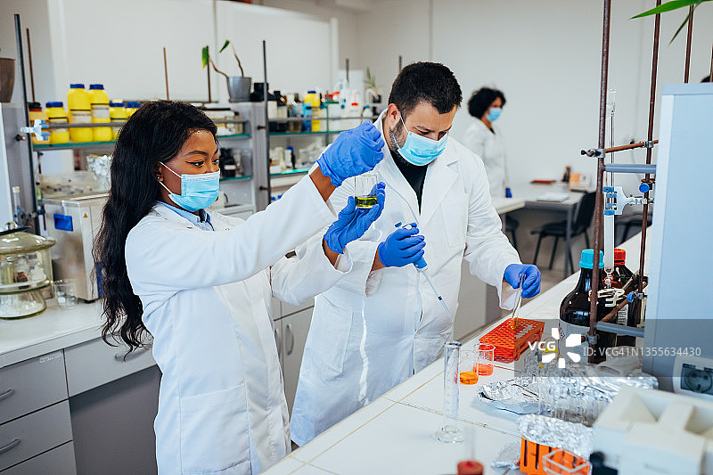 在实验室里做实验、混合液体溶液和测试的科学家图片素材