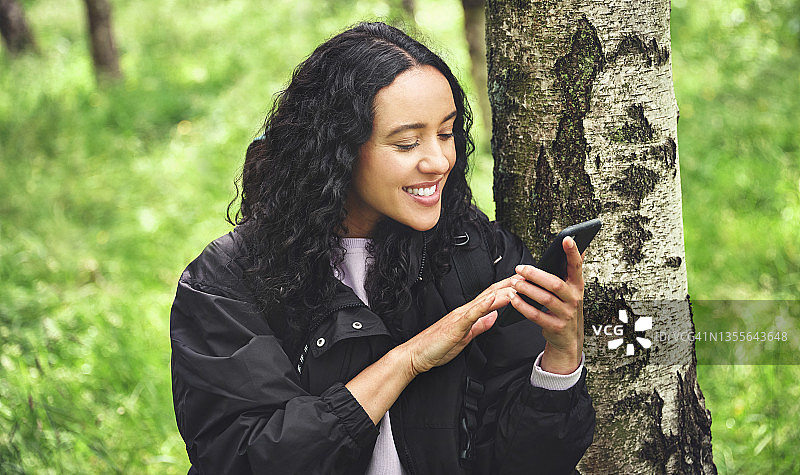 森林中徒步使用手机的年轻女人图片素材