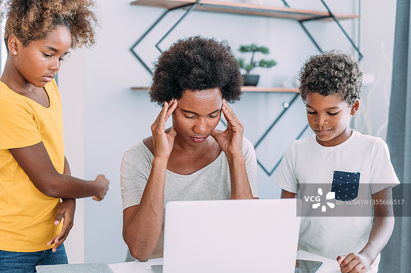 母亲在家工作，孩子们在一旁打扰图片素材