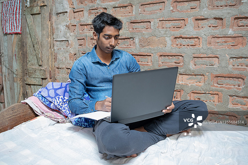 在经济状况不佳的家庭参加网络课程的印度男孩。图片素材