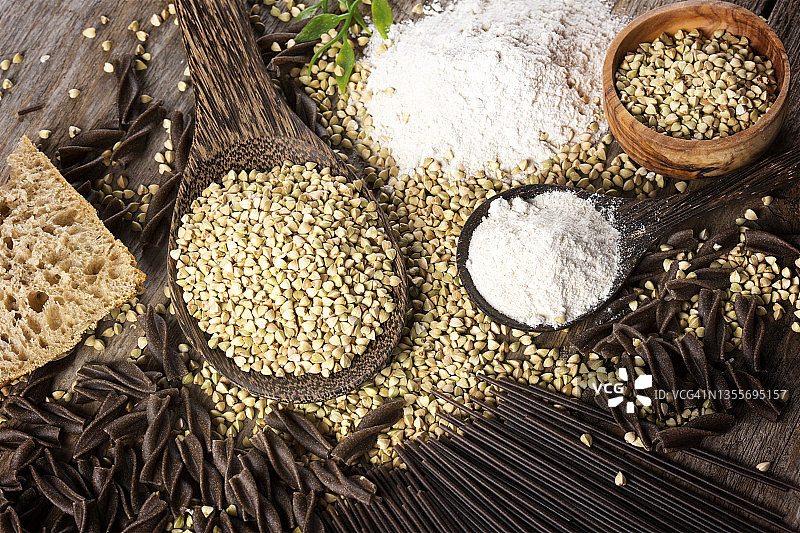 木碗中的全麦荞麦、荞麦面和乡村木桌上的面粉图片素材