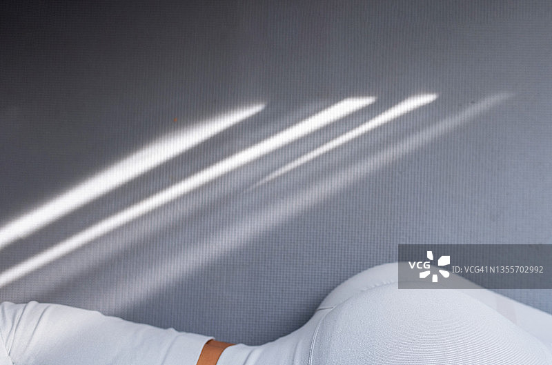 穿着运动服的女子躺在灰色地毯上的纤细腰部图片素材