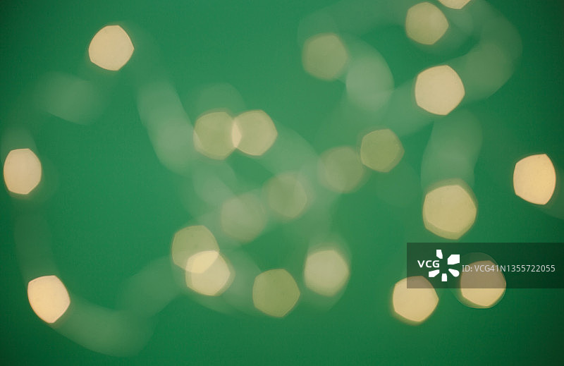 翠绿色背景上的金色散景虚化灯光，节日圣诞或新年背景图片素材