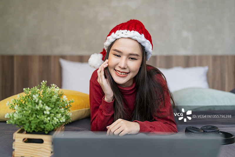 亚洲女性在卧室使用笔记本电脑上网和刷社交媒体，享受圣诞假期图片素材