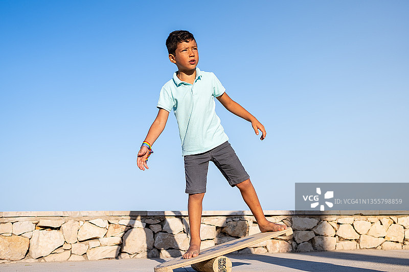 男孩站在木板上保持户外平衡图片素材