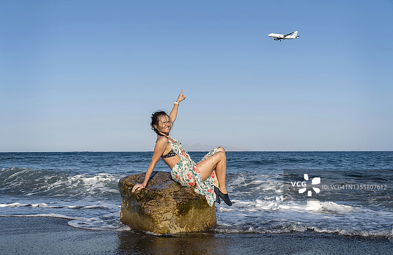 女人在飞机上展示她的手，欣赏海滩图片素材