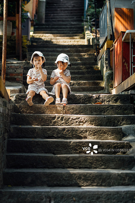 夏季，楼梯上坐着3岁的双胞胎姐妹图片素材