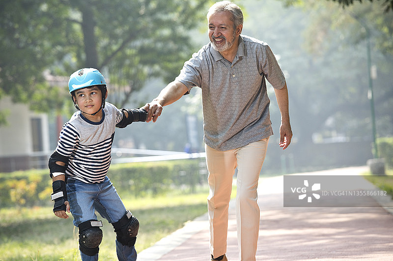 爷爷帮助孙子在公园滑冰图片素材