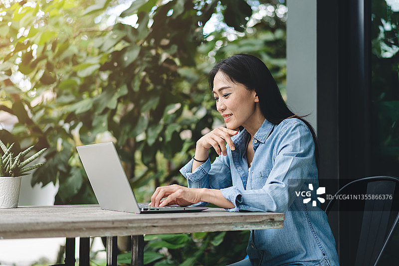 快乐的亚洲女人在户外使用笔记本电脑工作图片素材