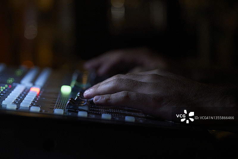 音响工程师在现场音乐会上调整调音台的特写镜头图片素材