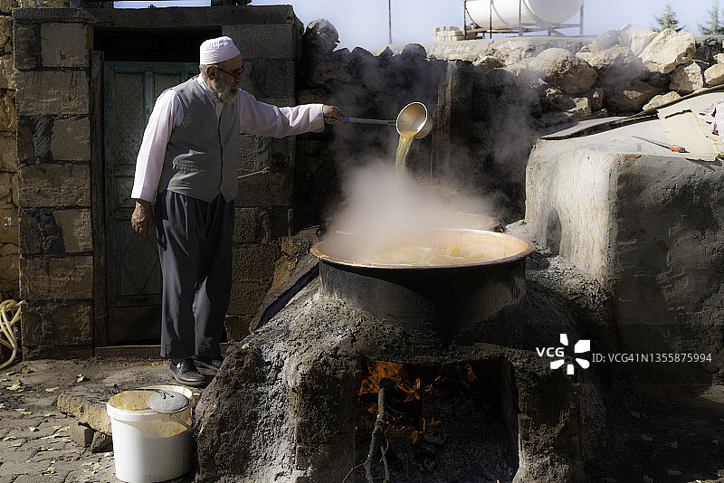 男人在壁炉火上用锅制作糖浆图片素材