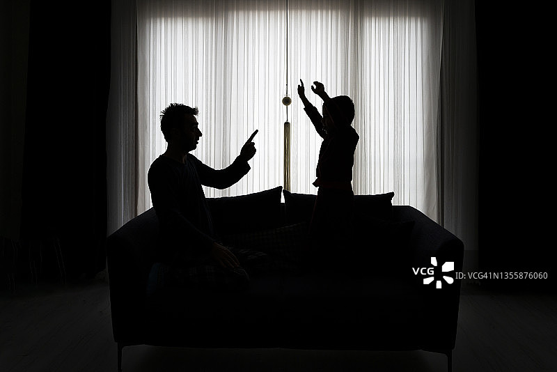 父亲在沙发上提醒儿子图片素材