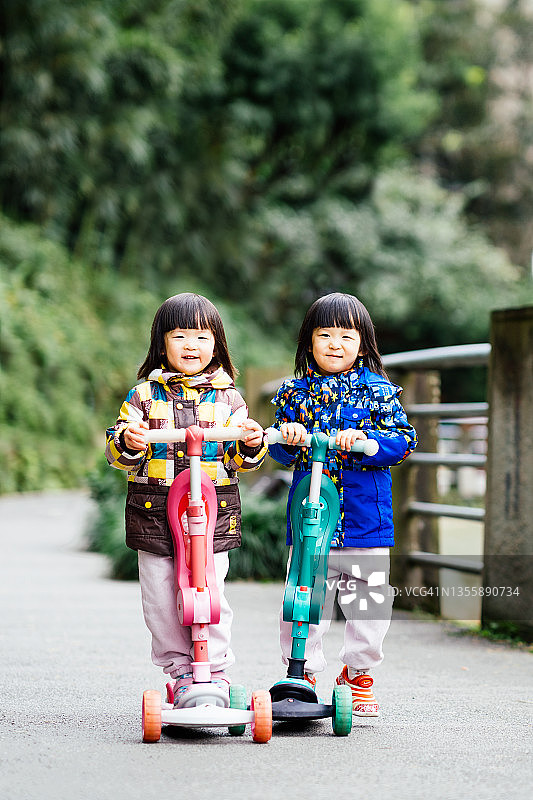 三岁双胞胎姐妹推动滑板车图片素材