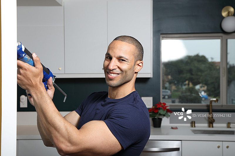 土耳其男子微笑看着镜头，手持填缝枪图片素材