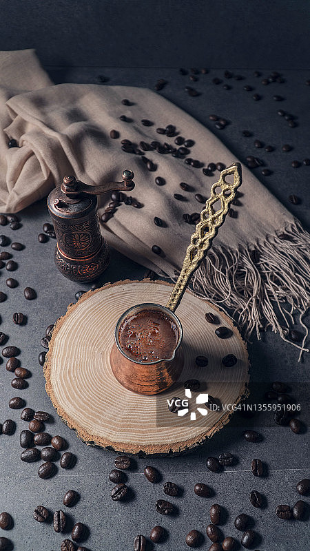 土耳其咖啡的特写镜头。地上有咖啡豆。后面有个咖啡研磨机。 铜咖啡壶。咖啡和研磨机。图片素材