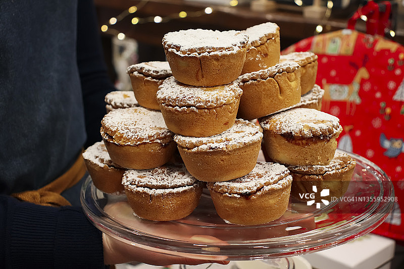 端着一盘堆满肉馅饼的人，侧视图，背景有圣诞灯图片素材
