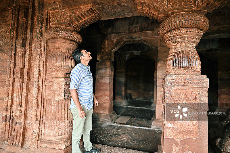 男人在印度卡纳塔克邦巴达米看着一座古老的印度教石庙中的石雕图片素材