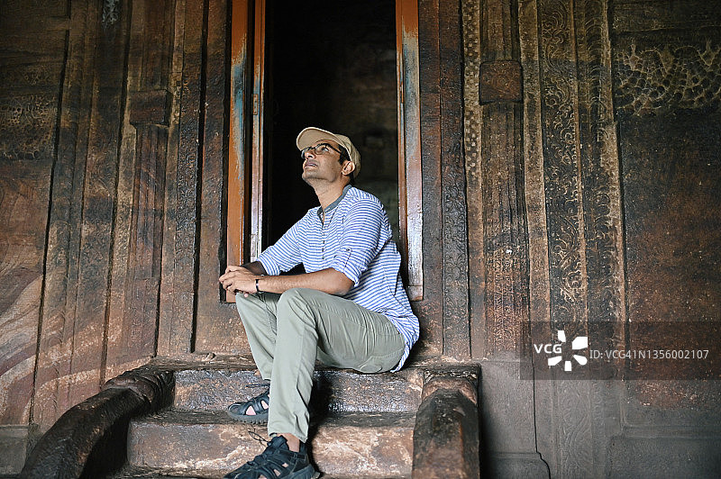 男人在印度卡纳塔克邦巴达米看着一座古老的印度教石庙中的石雕图片素材